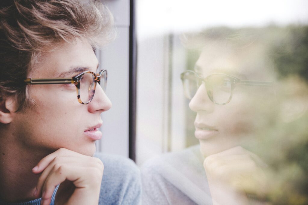 Man looking out window with reflection of his face in window