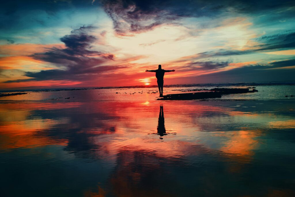 Person embracing beautiful sunset on beach.