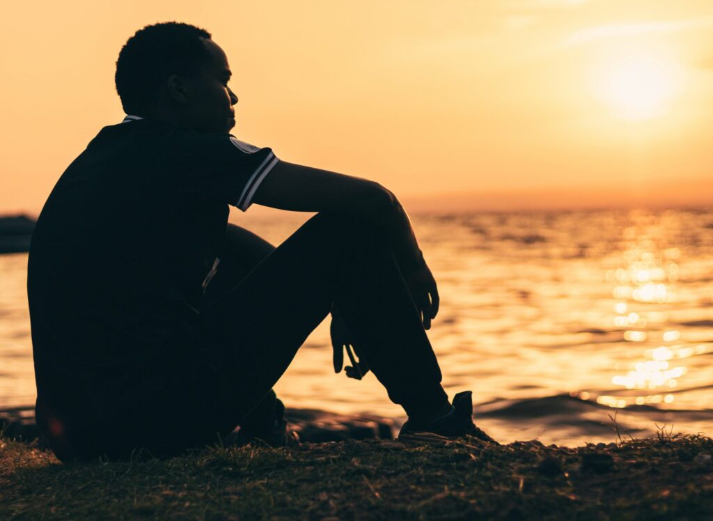 Reflective person sitting near ocean